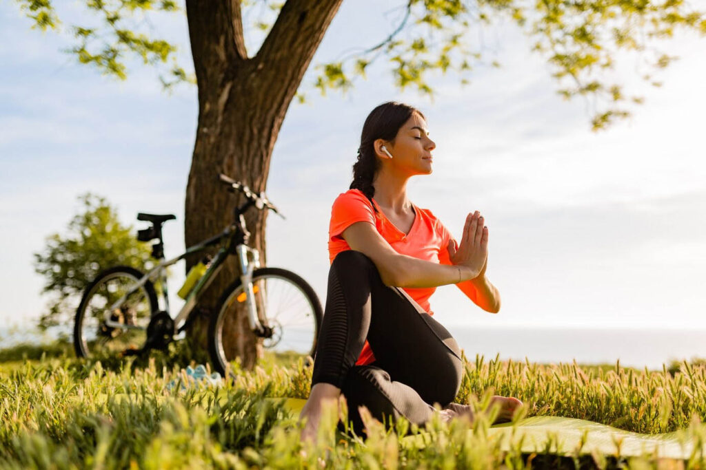 ciclista meditando em um jardim com grama verde em baixo de uma árvore